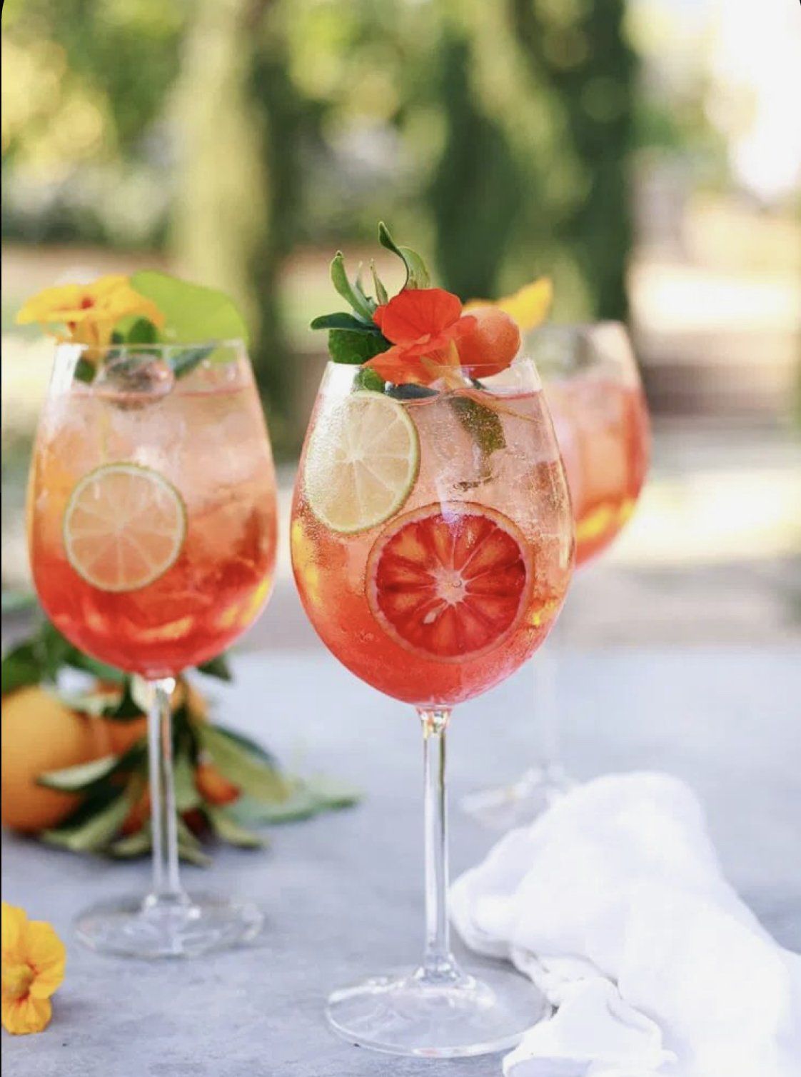 Three wine glasses filled with a red drink on a table.
