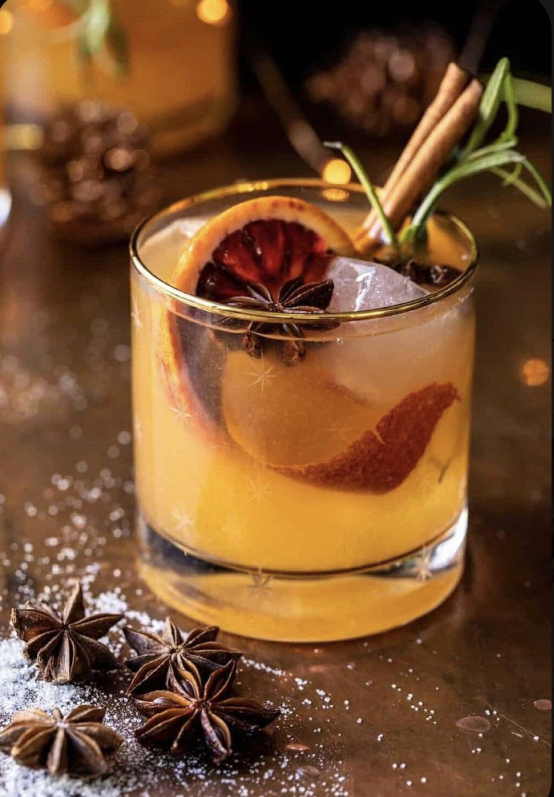 A glass of orange juice with cinnamon sticks and star anise on a table.