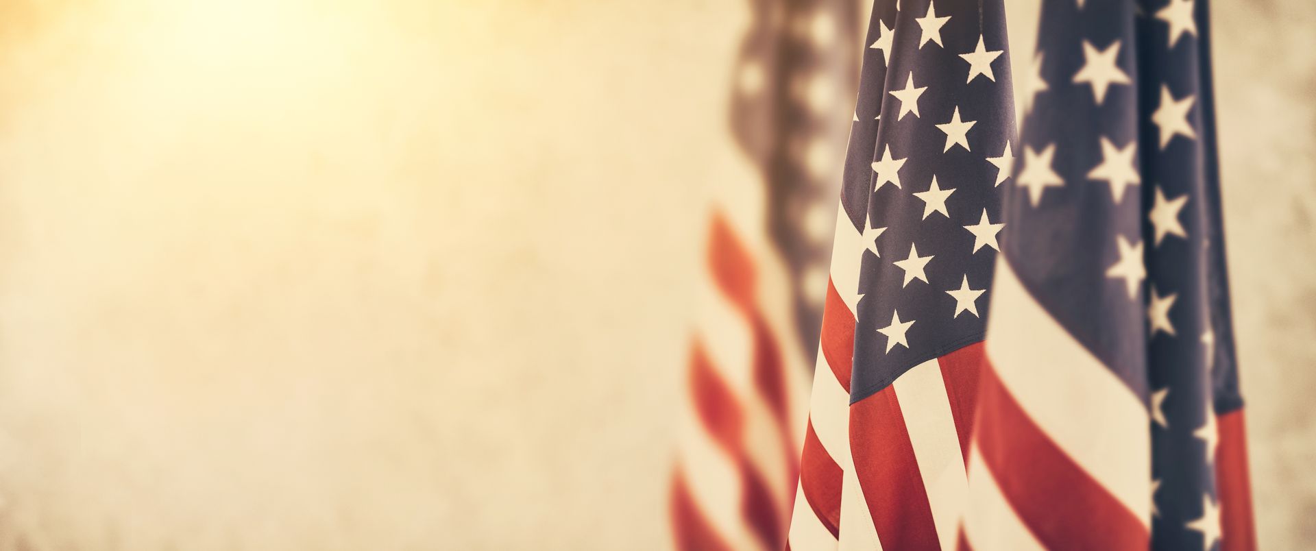 A woman is holding an american flag and a rose at a funeral.