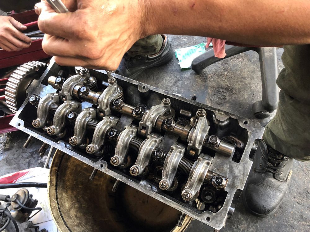 Person working on car engine cylinder head, tools visible — P.K. Head Servicing & Reconditioning in Warilla, NSW