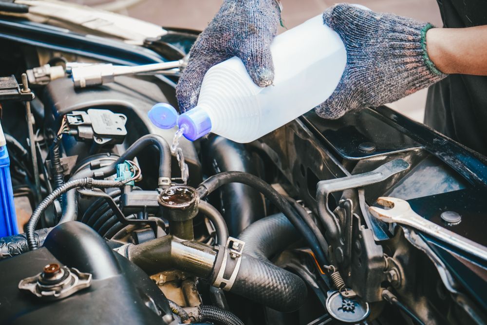 Mechanic Pouring Fluid Into a Car Engine — P.K. Head Servicing & Reconditioning in Warilla, NSW