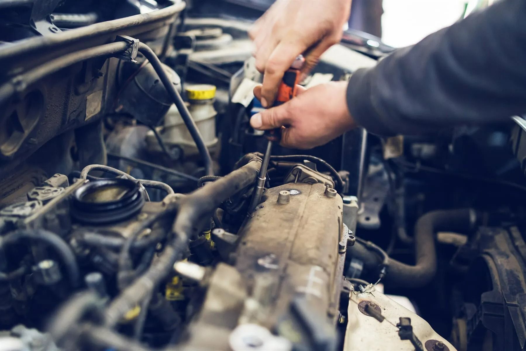 Mechanic Using a Screwdriver to Work on a Car Engine — P.K. Head Servicing & Reconditioning in Warilla, NSW