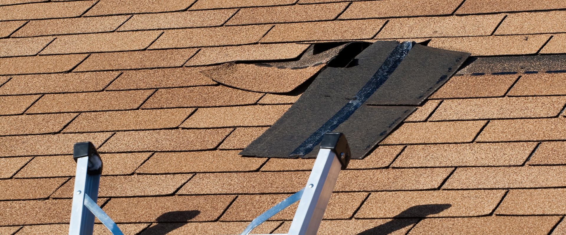 A ladder is sitting on top of a roof with a hole in it.