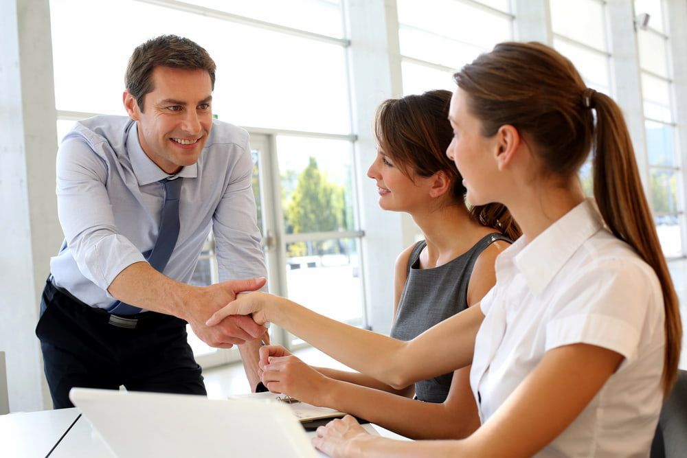 Man Shaking Hands With Woman at a Desk in an Office — Curtis Strata in Byron Bay, NSW