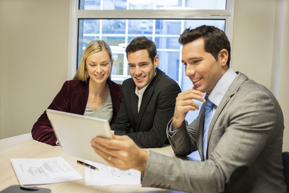 A Financial Advisor Shows a Tablet to a Couple at a Table in an Office — Curtis Strata in Kingscliff, NSW