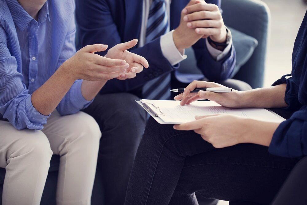 Two People in a Meeting With a Person Holding a Clipboard, Discussing Paperwork — Curtis Strata in Lismore, NSW
