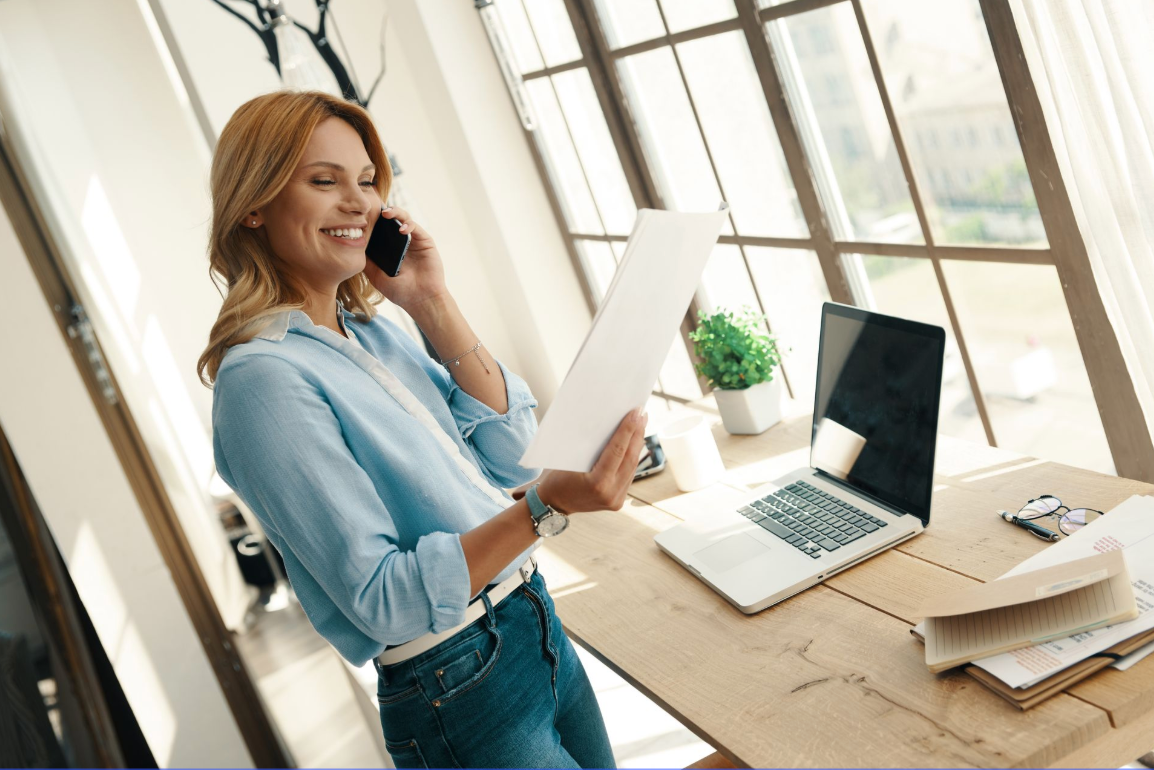 Woman talking on the phone with a laptop in front of her.