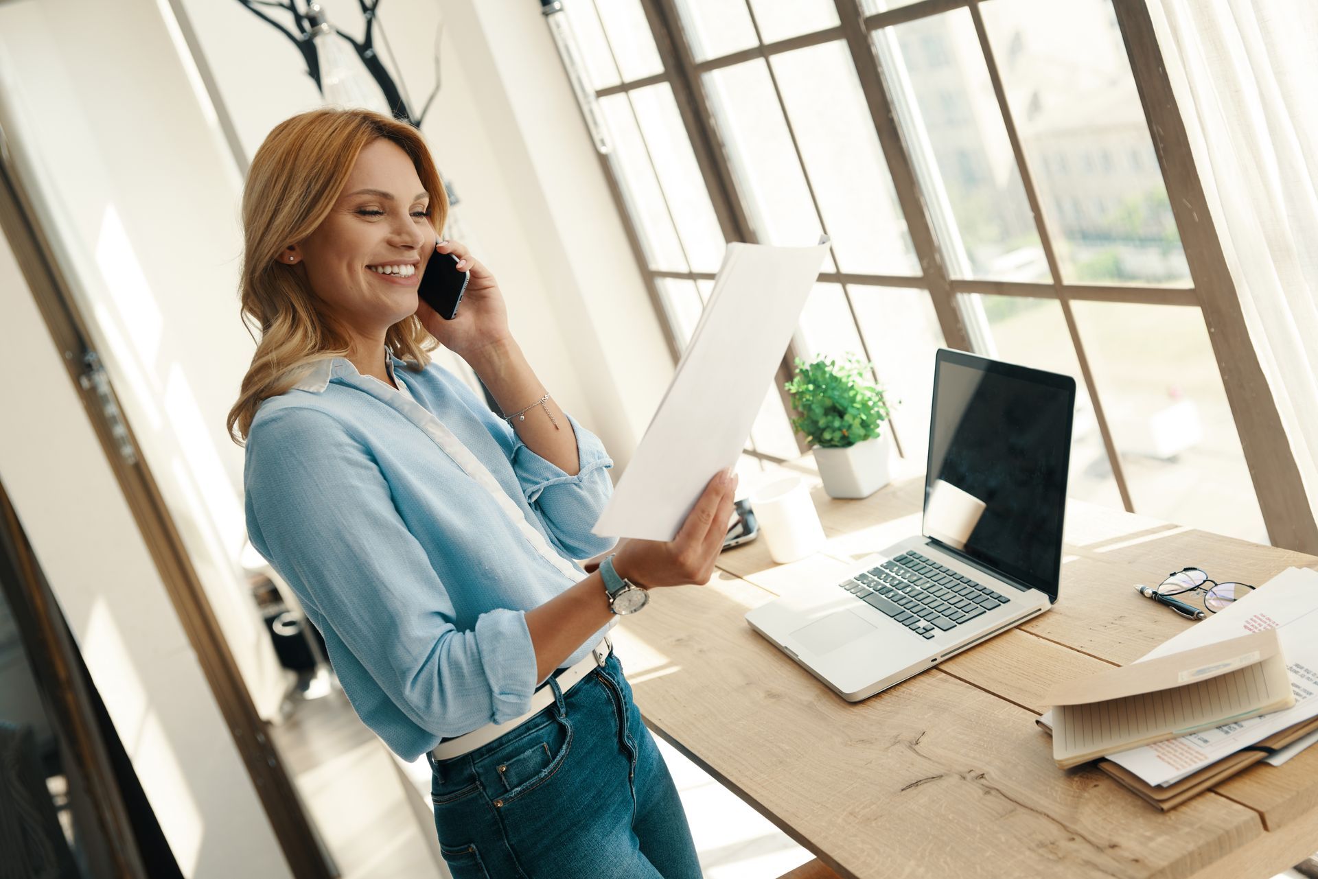 Woman talking on the phone with a laptop in front of her.