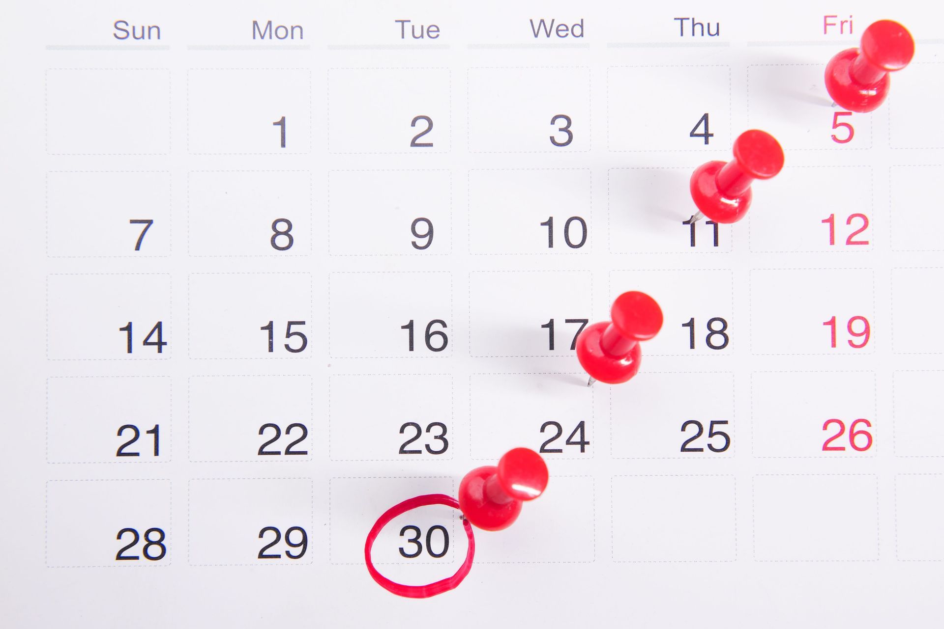 Calendar with thumbtacks pushed into multiple dates.
