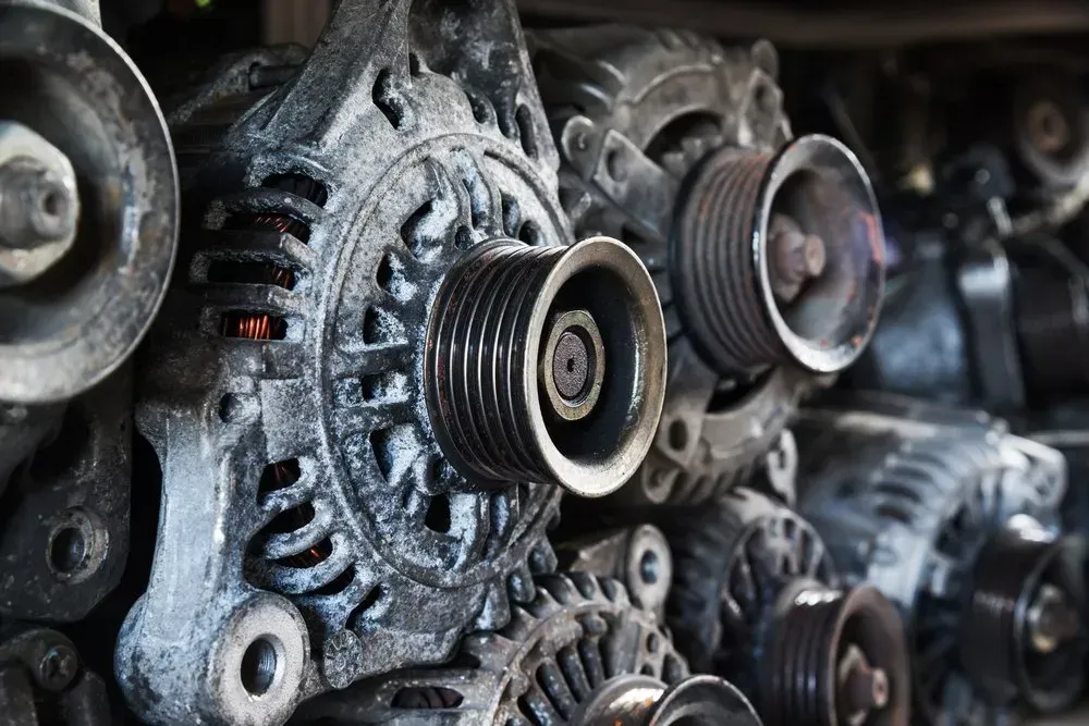 Pile of Used Car Alternators With Pulleys, Metal, Dark Setting — Independent Scrap Metal Pty Ltd in Casino, NSW