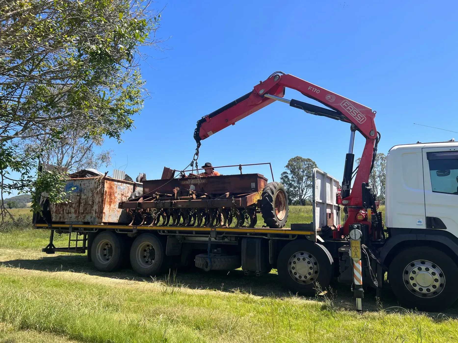 A Red Crane Loading a Rusty Farm Implement Onto a Flatbed Truck — Independent Scrap Metal Pty Ltd in South Lismore, NSW