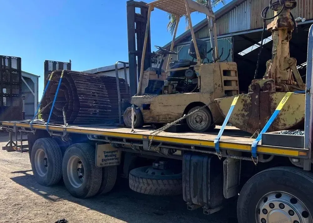 Flatbed Truck Carrying a Forklift and Large Circular Metal Objects — Independent Scrap Metal Pty Ltd in South Lismore, NSW