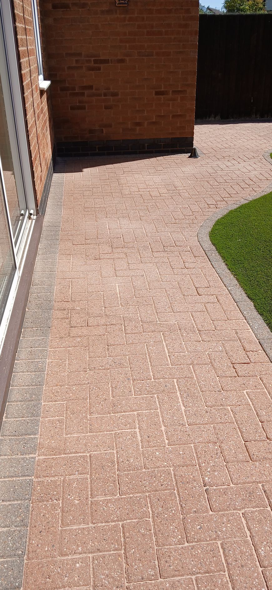 A block paved patio in front of a brick house after being pressure washed and re-sanded by benchmark property services.