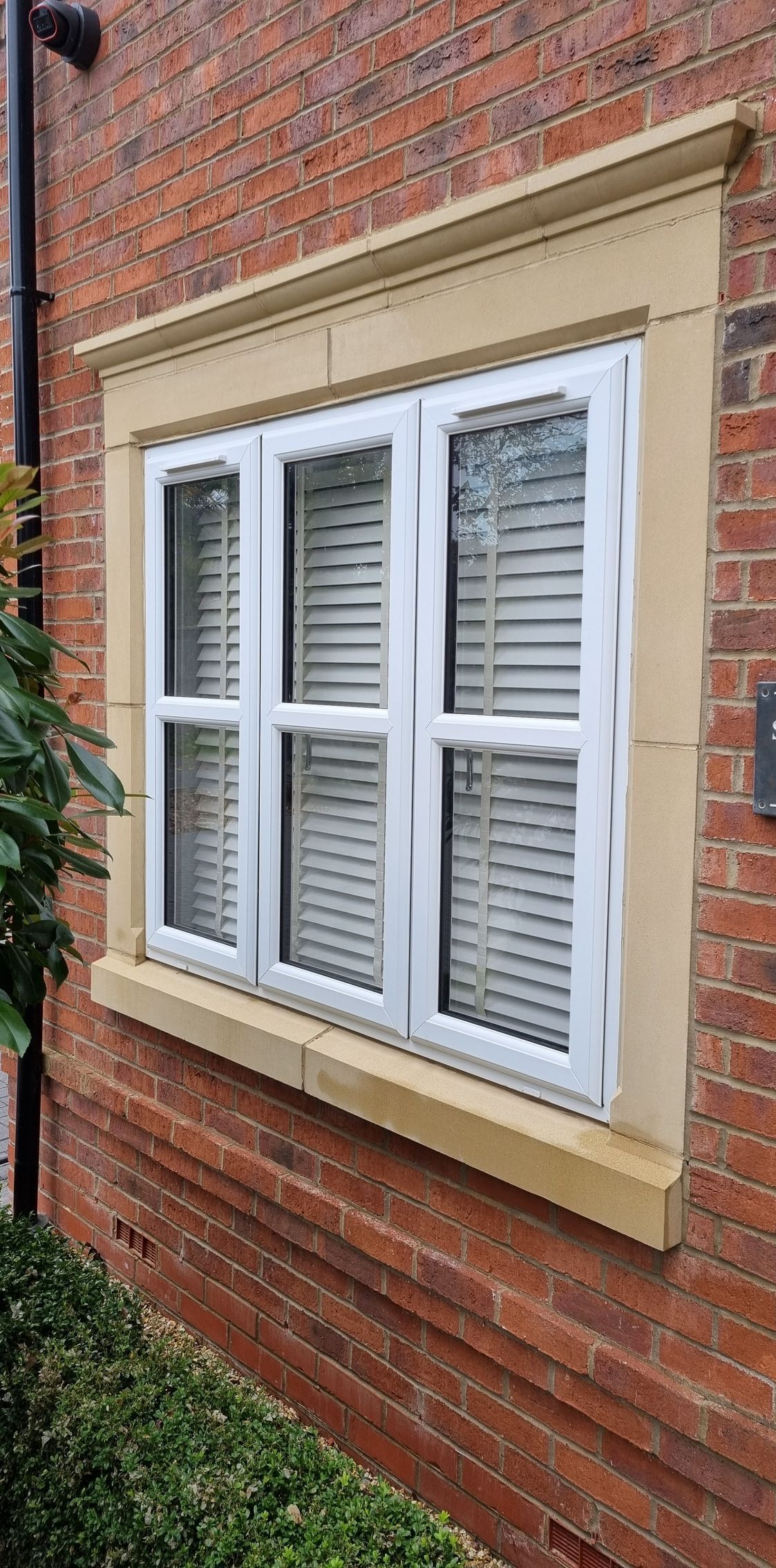 A white window is on the side of a brick building.