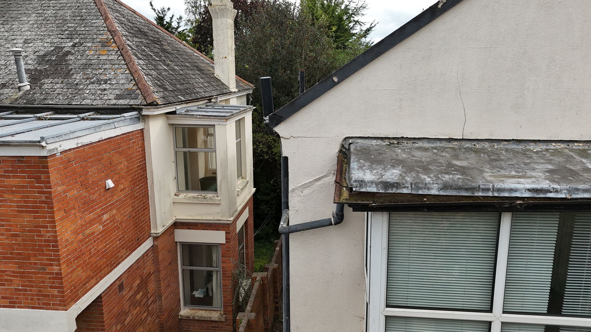 Drone roof survey showing defective gutter and crack to wall render.