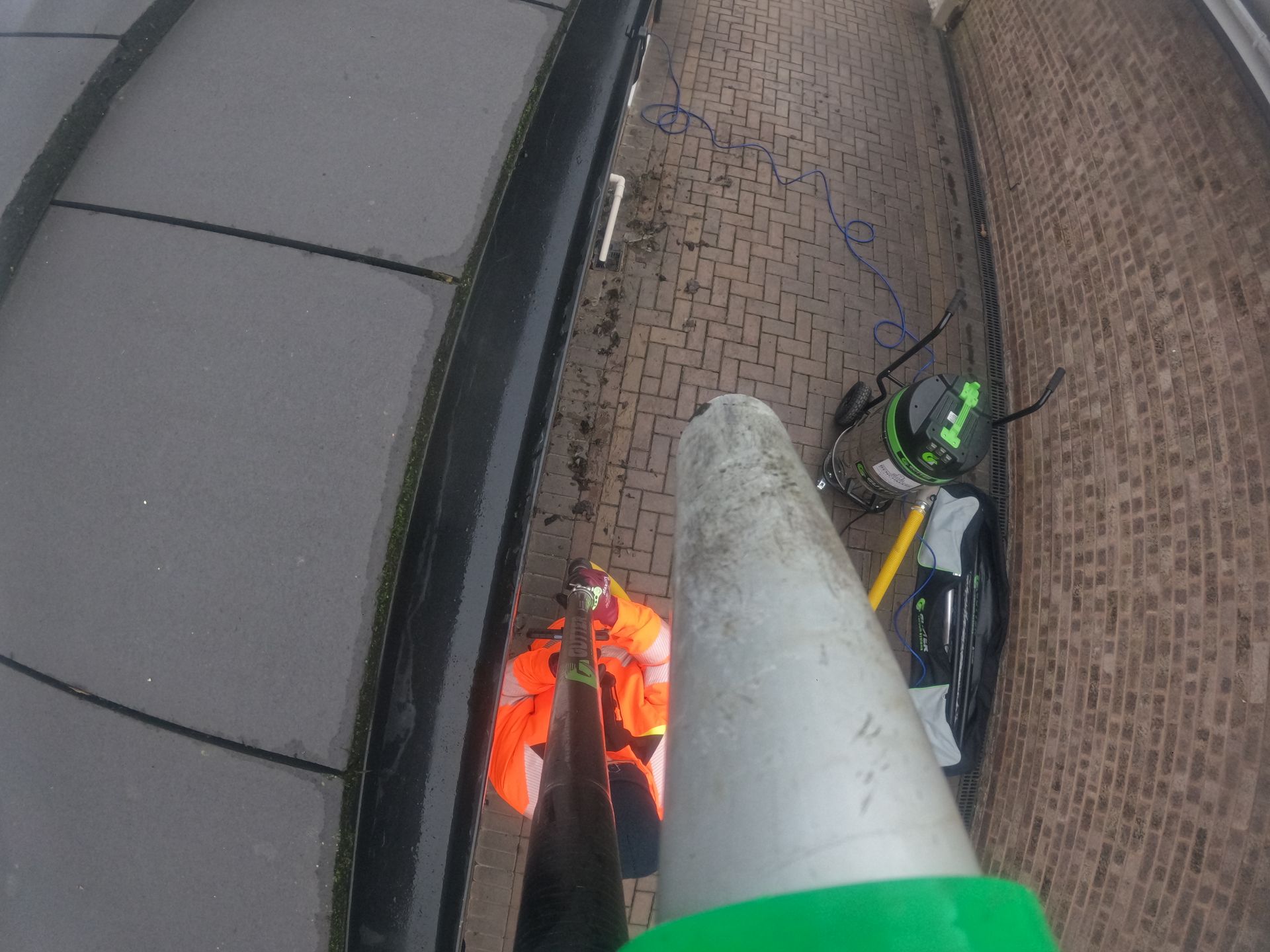 A man in an orange jacket using a Gutter Vacuum with camera