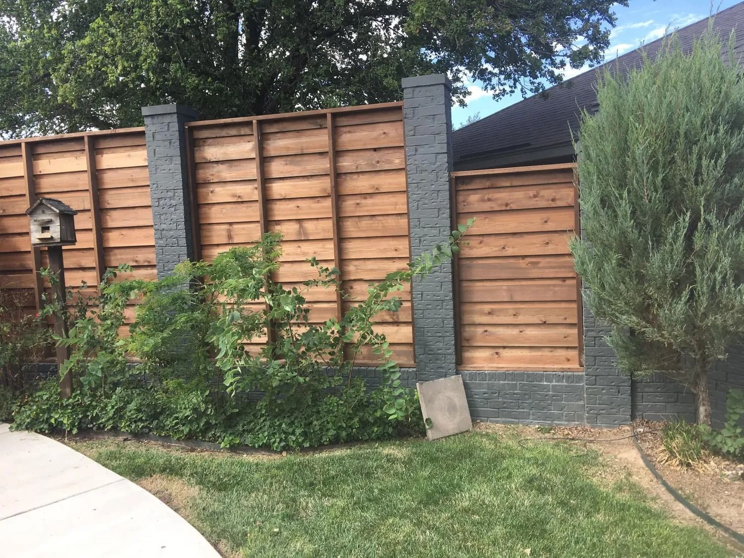 Wooden fence with dark brick posts and landscaping.