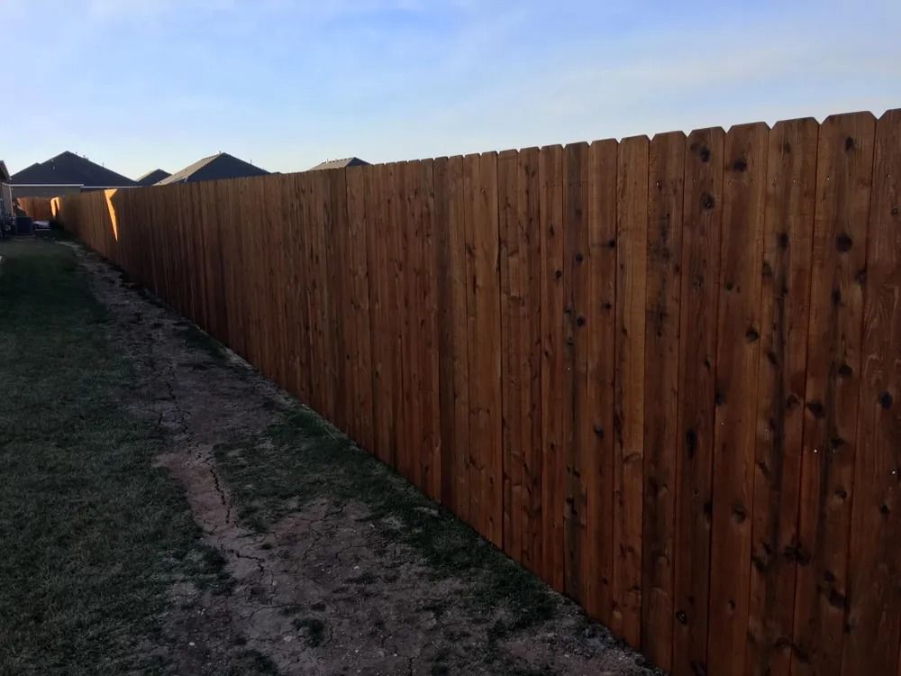 Wooden privacy fence in a yard, extending into the distance.
