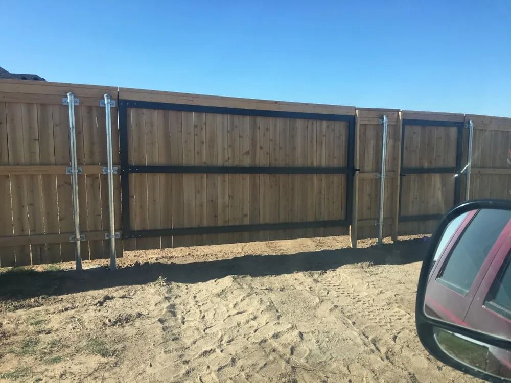 Wooden fence with a gate, metal framing, and a car side mirror in view.