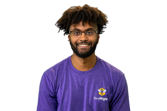 Man with glasses smiles, wearing a purple long-sleeve shirt. White background.