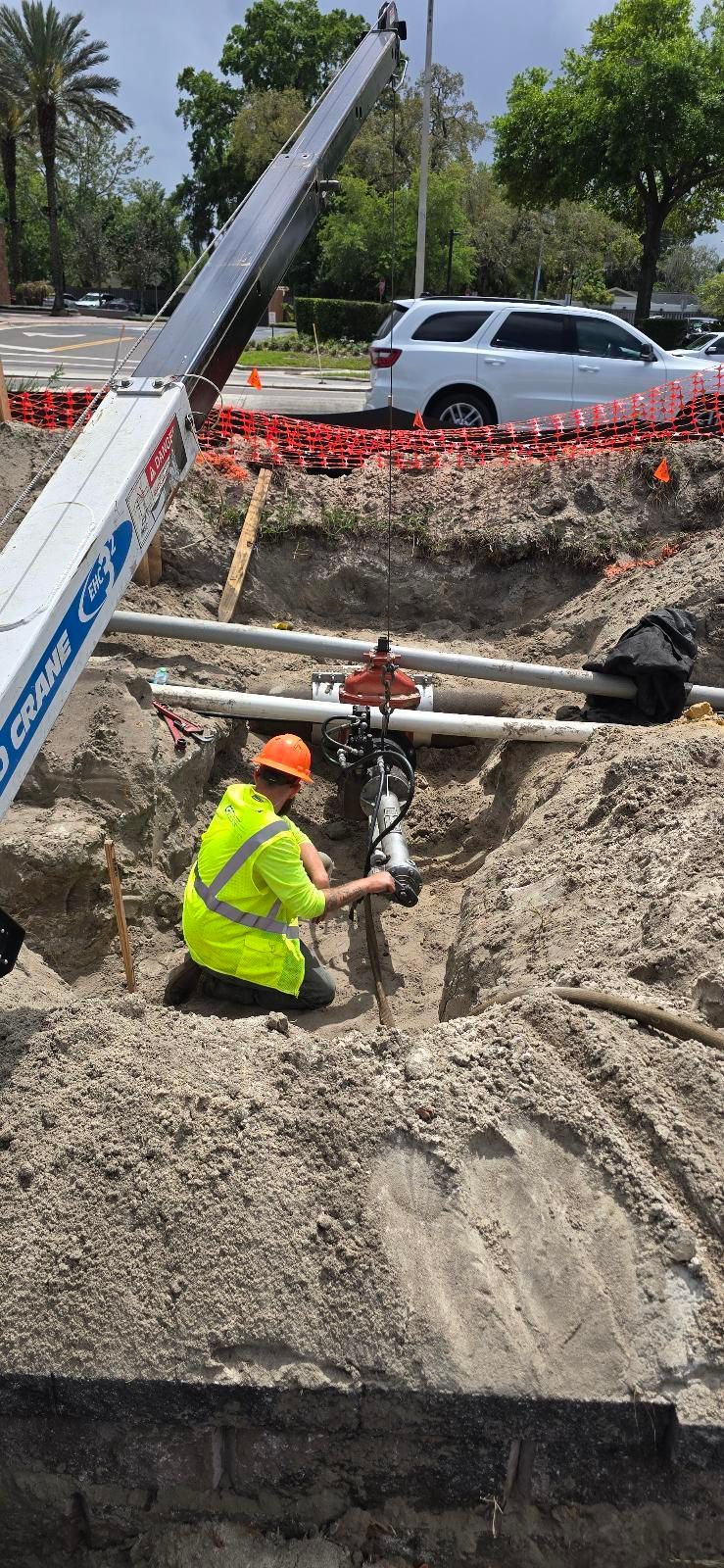 Workers in trench, one wearing neon green, other in orange, working on underground utilities.