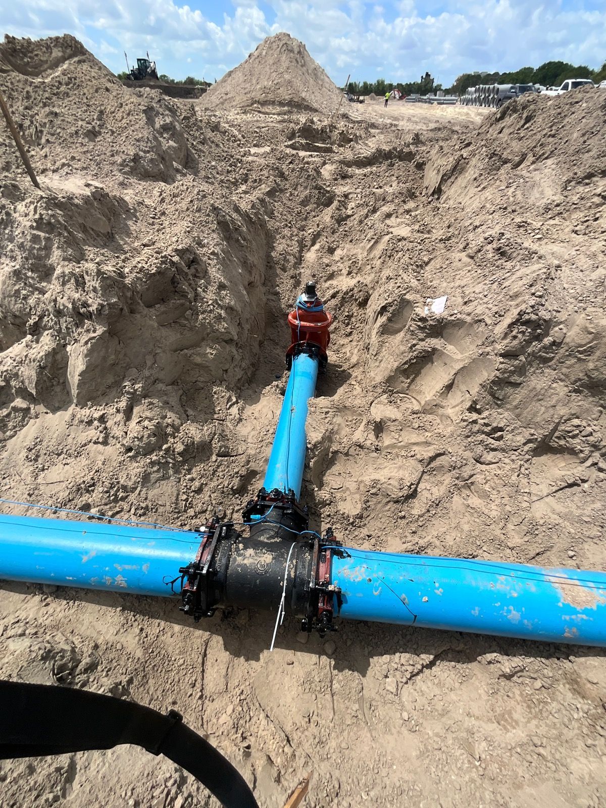 Construction workers in trench working on large pipe.