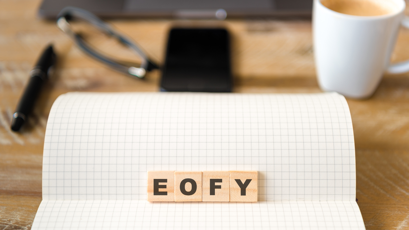 The word eofy is written in wooden blocks on a notebook.