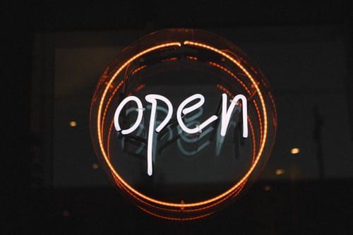 A neon sign that says `` open '' is lit up in the dark.