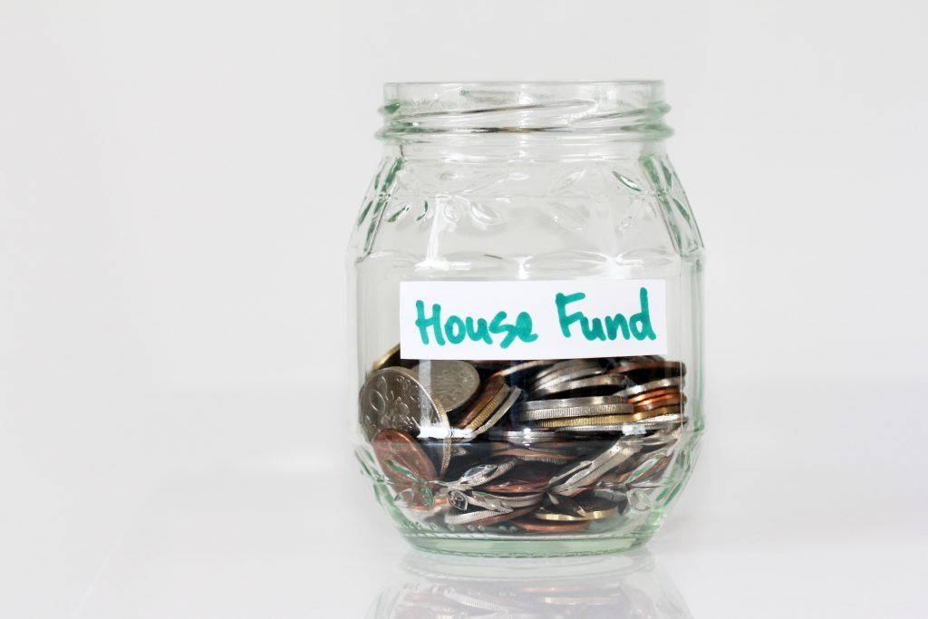 A jar filled with coins and a label that says house fund