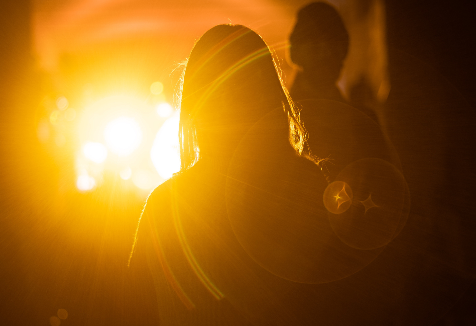 A person in a hood is standing in front of a bright light.