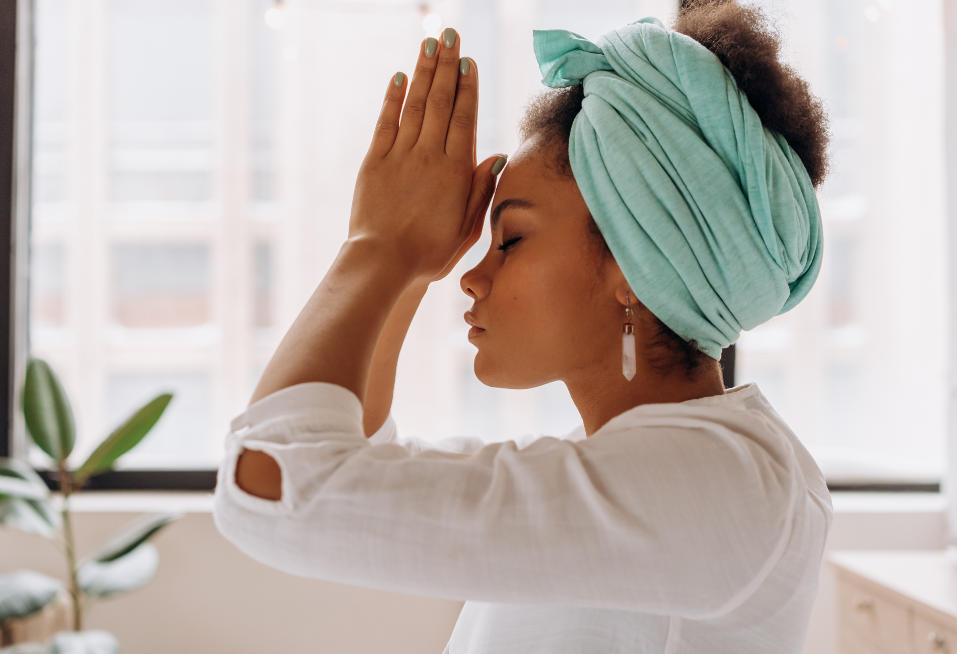 A woman wearing a turban is meditating with her hands on her forehead.