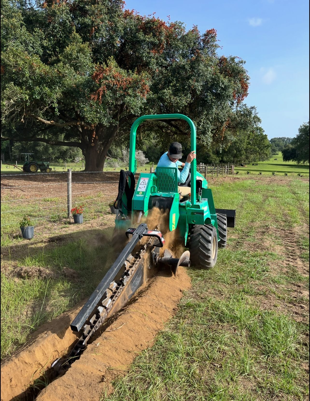 A man is driving a green tractor in a field.