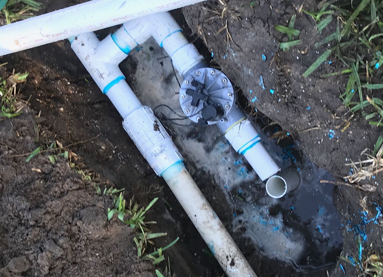 A bunch of pipes are laying in the dirt.