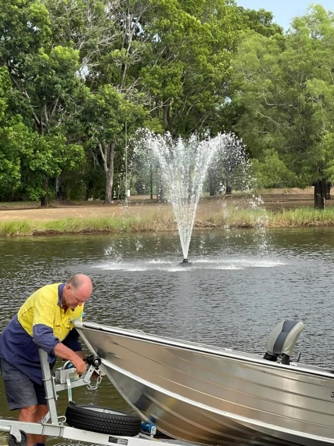 Man Working on a Boat by a Pond With a Water Fountain — iWater NT Pty Ltd in Yarrawonga, NT