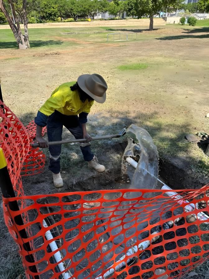 Person in Work Clothes Fixing a Pipe in an Open Area — iWater NT Pty Ltd in Yarrawonga, NT