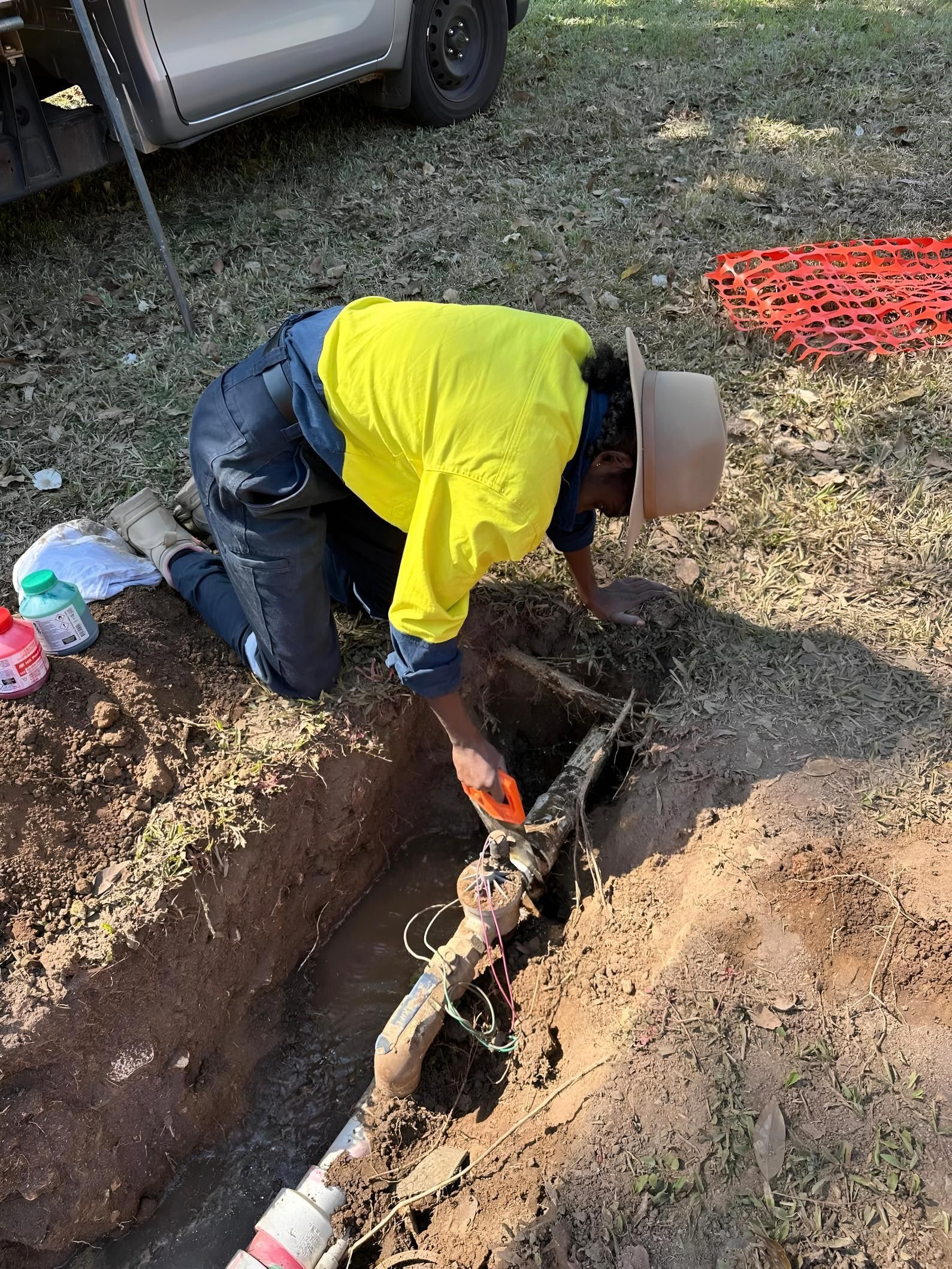 Worker in Yellow Shirt and Hat Repairs a Pipe in a Trench Outdoors — iWater NT Pty Ltd in Yarrawonga, NT