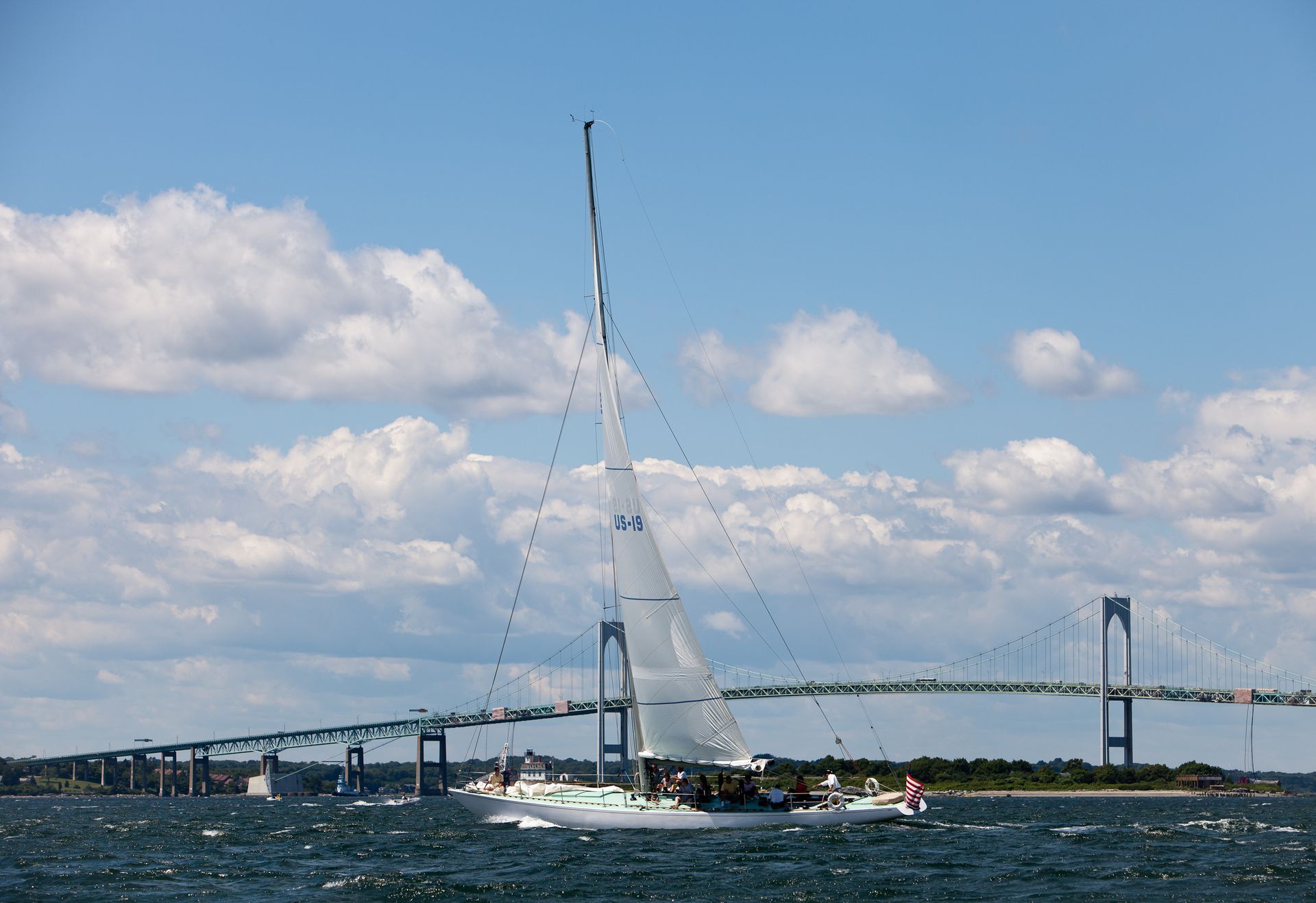 A sailboat in the water with a bridge in the background