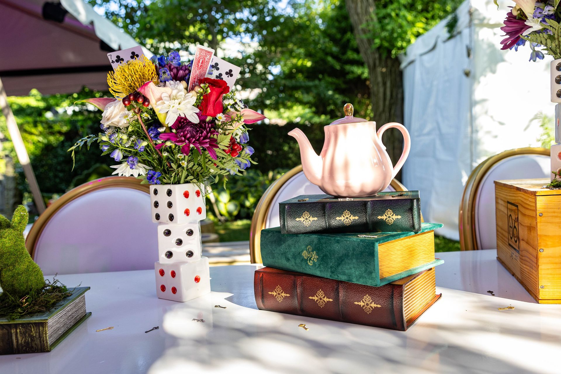 An Alice in Wonderland themed table with flowers, teapot, and books.
