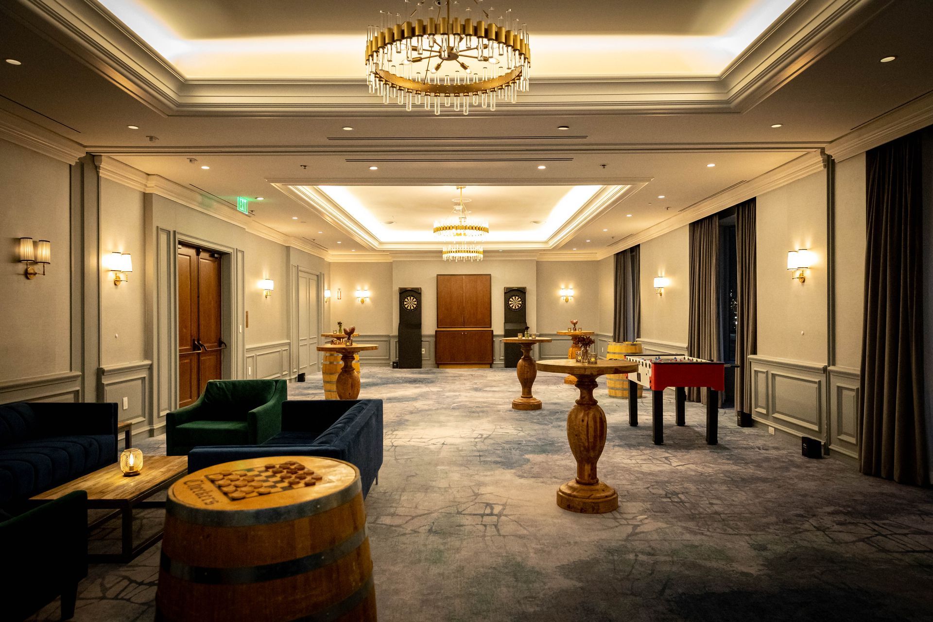 Formal event room with barrel tables, couches, and a foosball table.