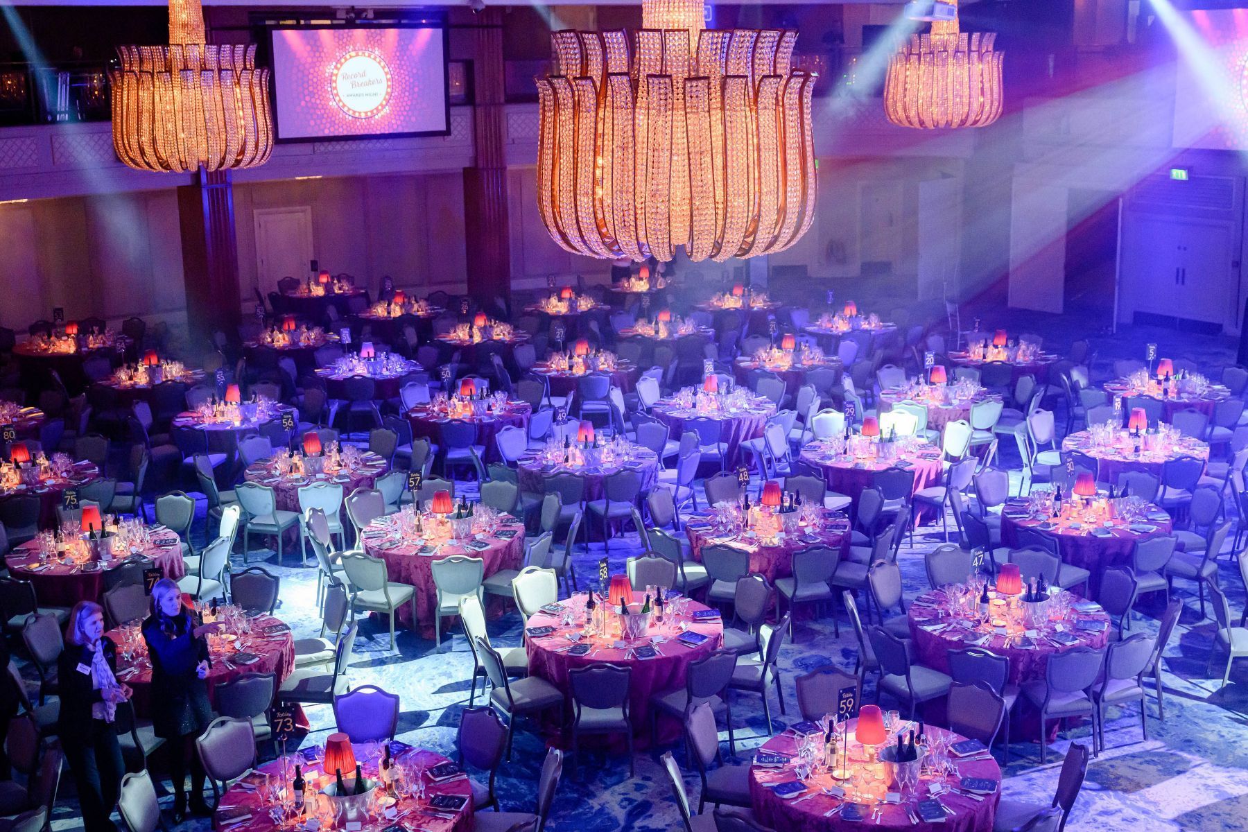 A large room filled with tables and chairs and a chandelier.