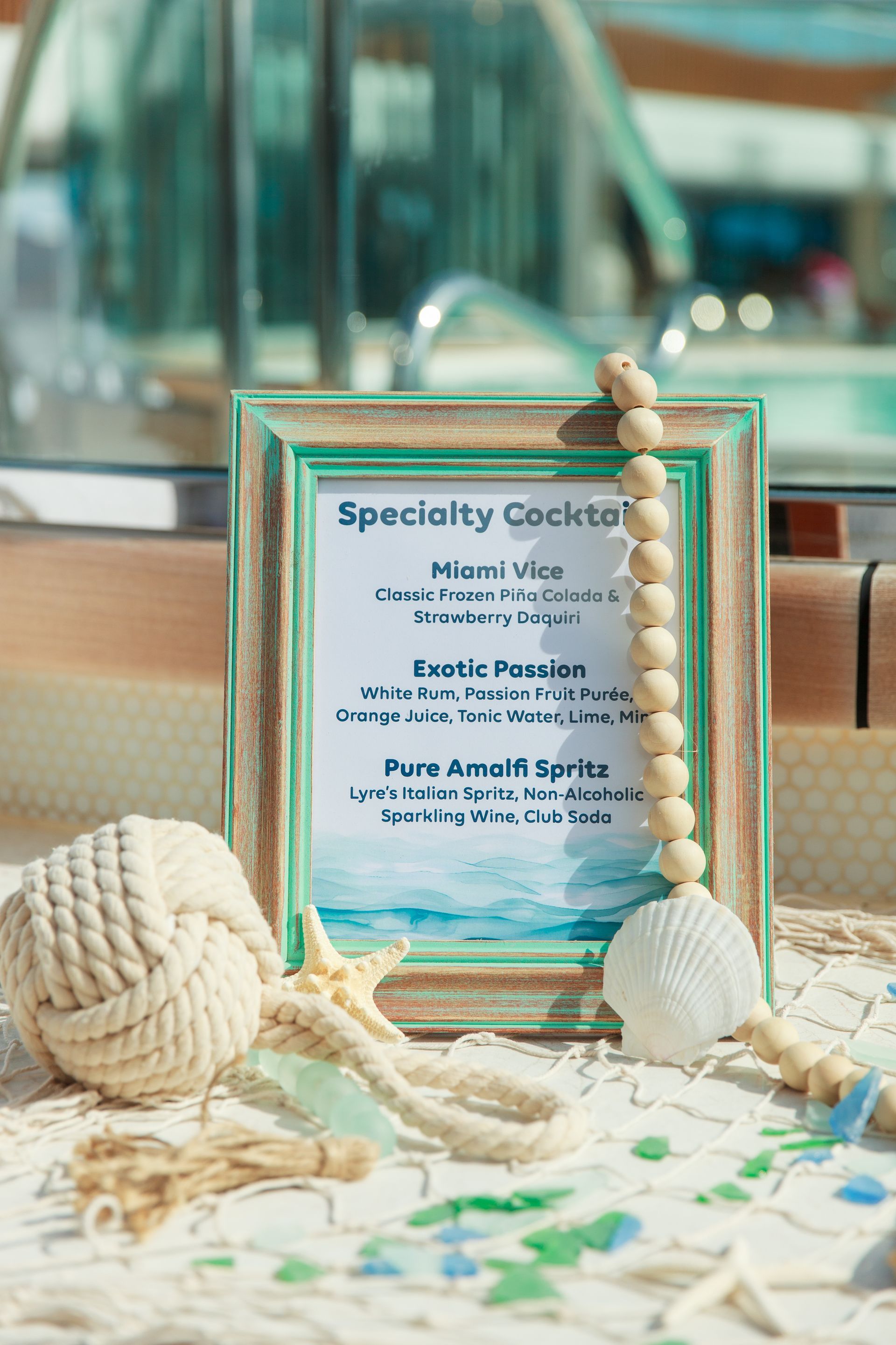 Cocktail menu sign with nautical decor, beach background.