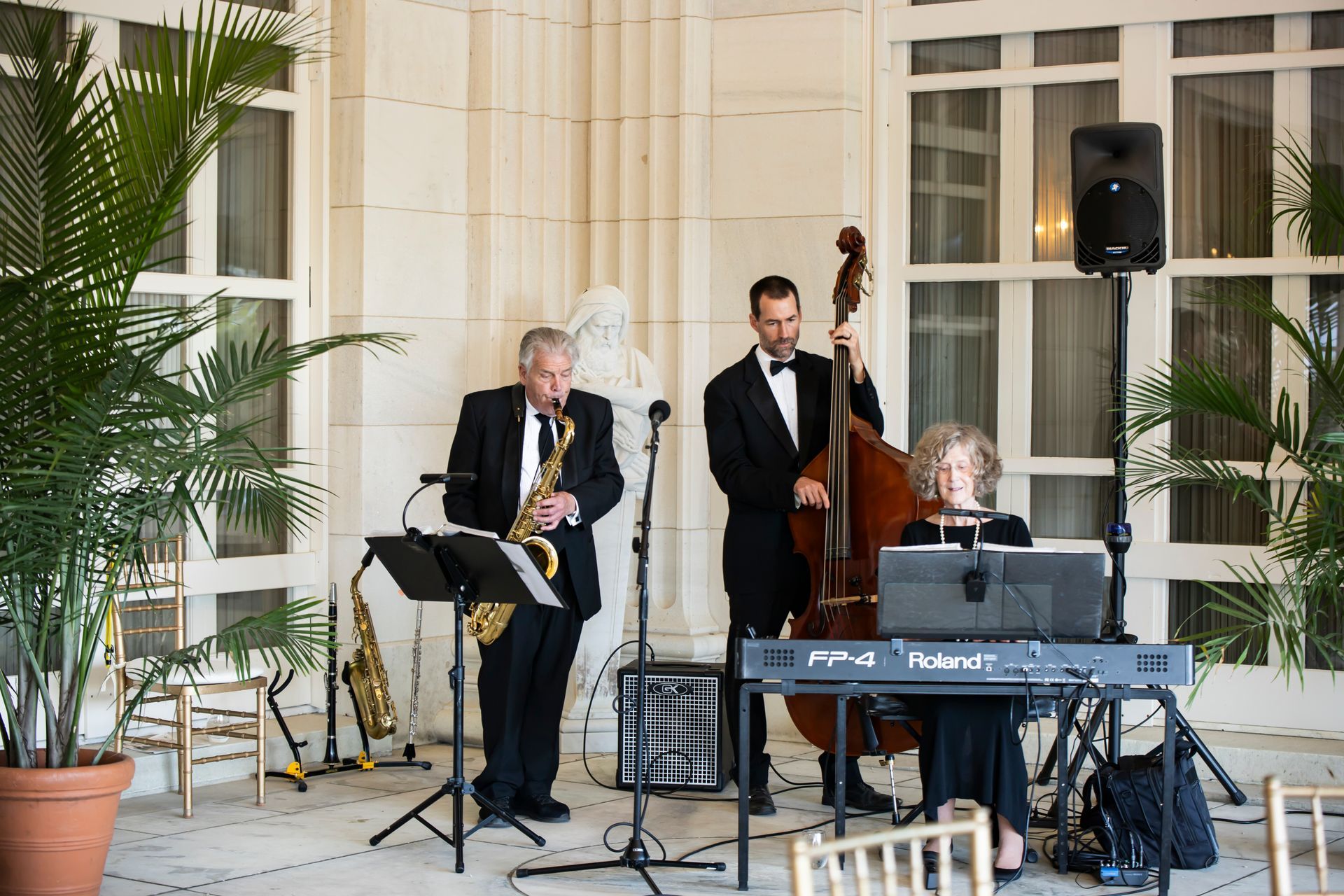 Jazz band playing at an outdoor venue; saxophone, bass, and keyboard.