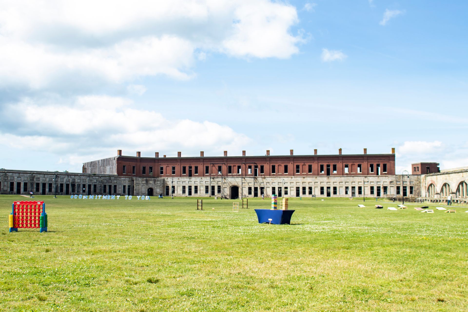 Fort with red brick and white stone walls, a green lawn, and a blue sky.