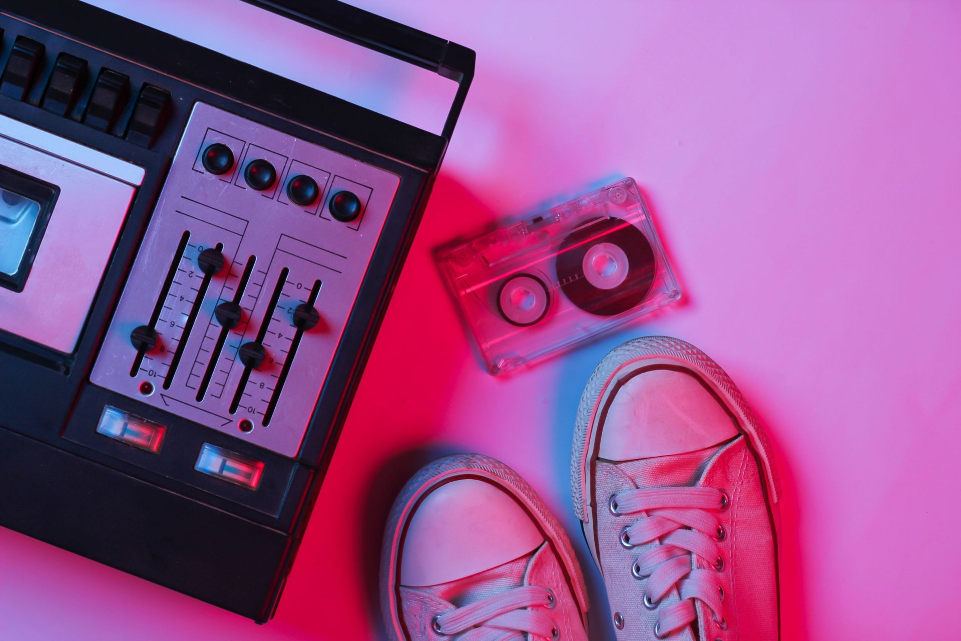 A pair of shoes , a tape recorder , and a cassette tape on a pink background.