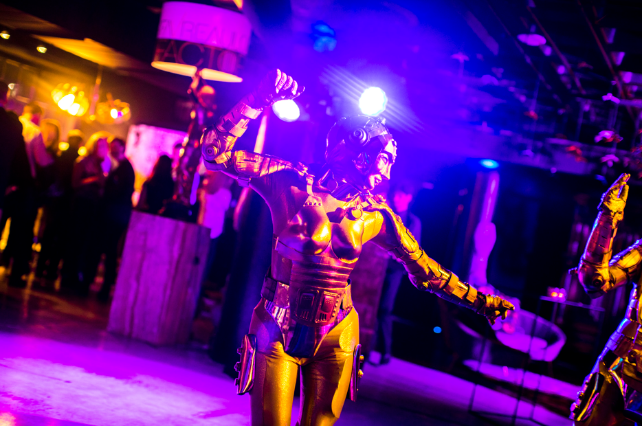 Person in metallic costume dances under purple spotlights at a party.