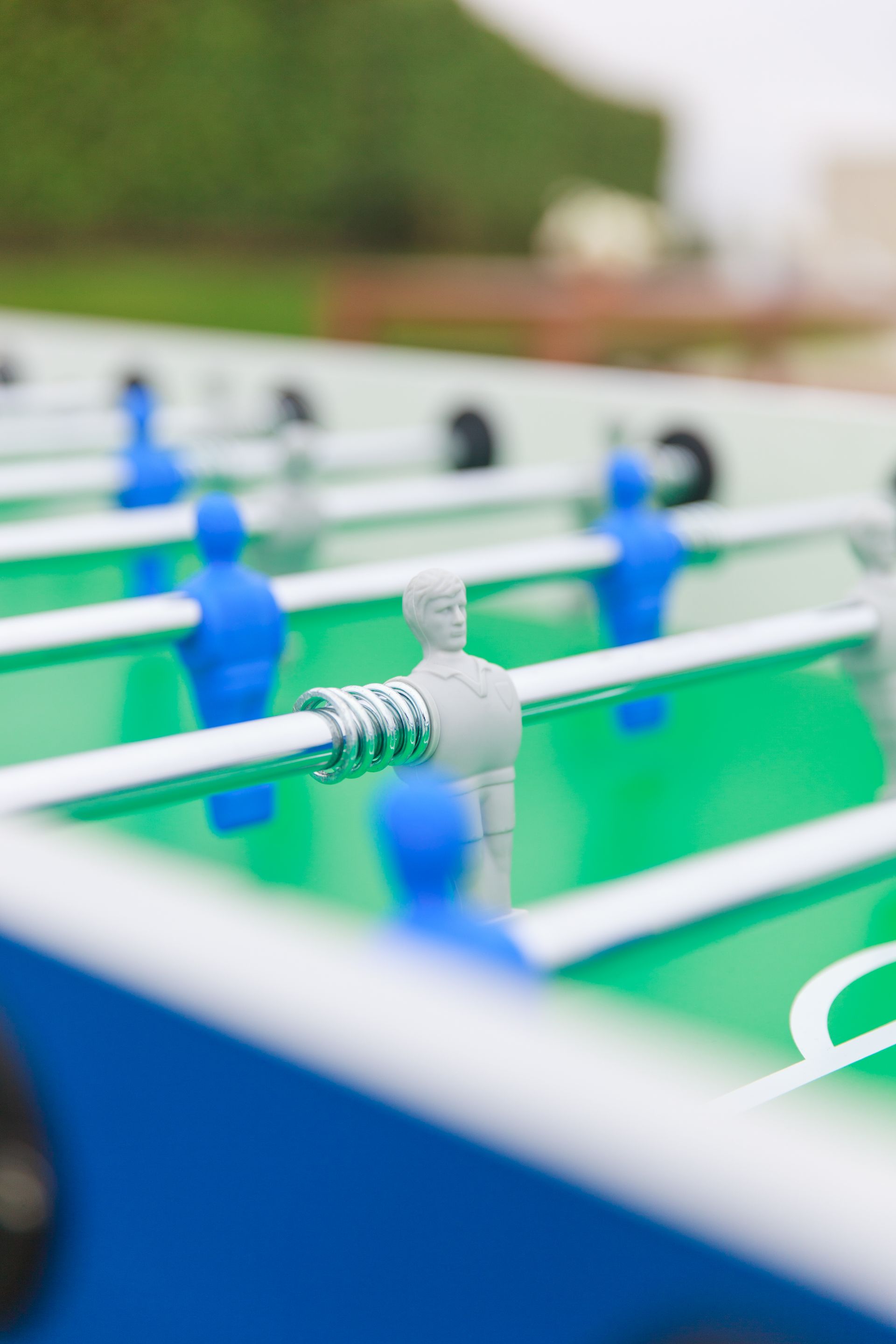 Foosball table, close-up. Blue and gray players face each other on a green playing surface.