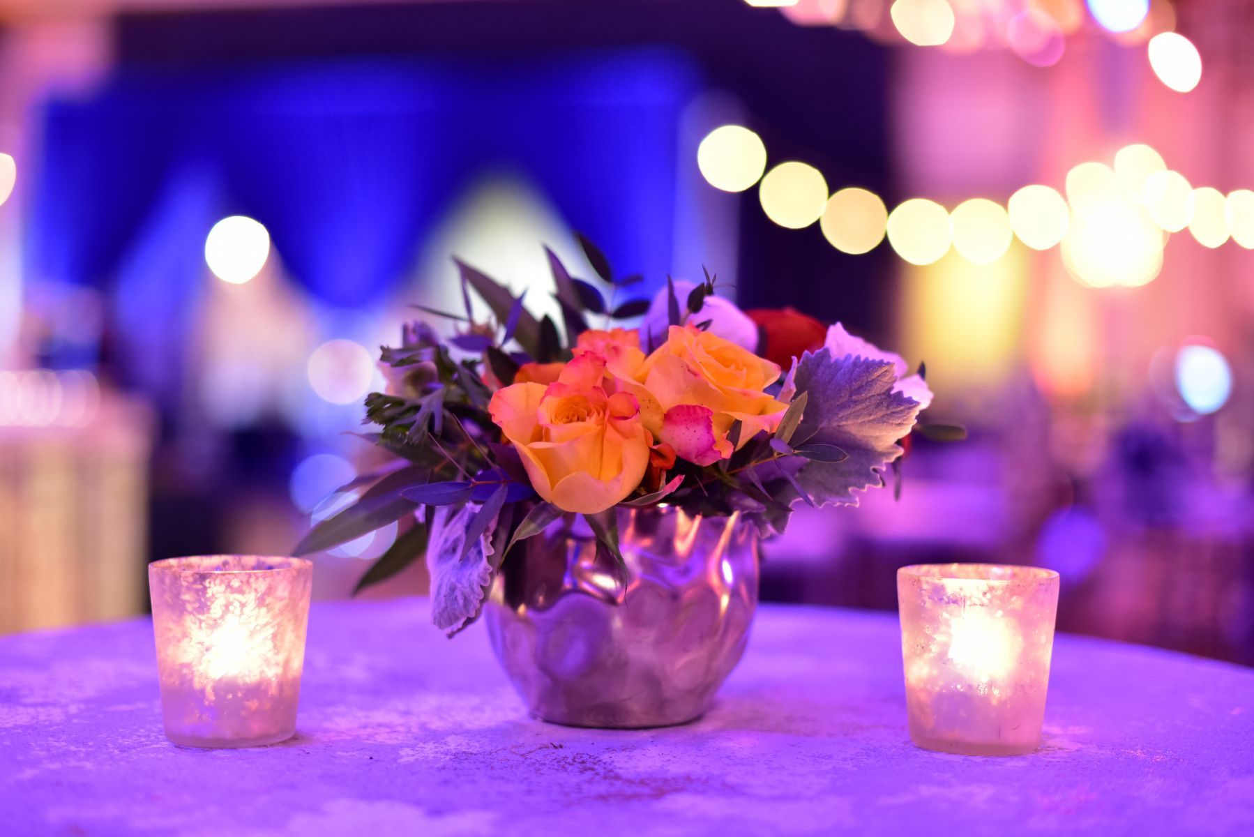 A vase of flowers is sitting on a table next to two candles.