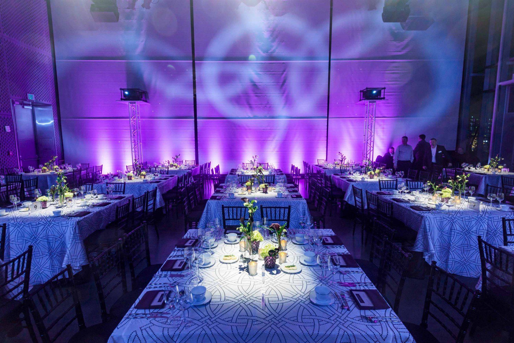 A large room filled with tables and chairs and purple lights.