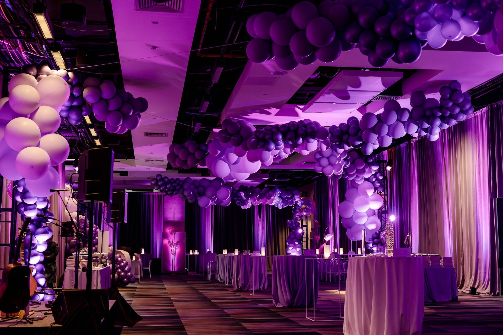 Purple lit event space with balloon decorations and tables.