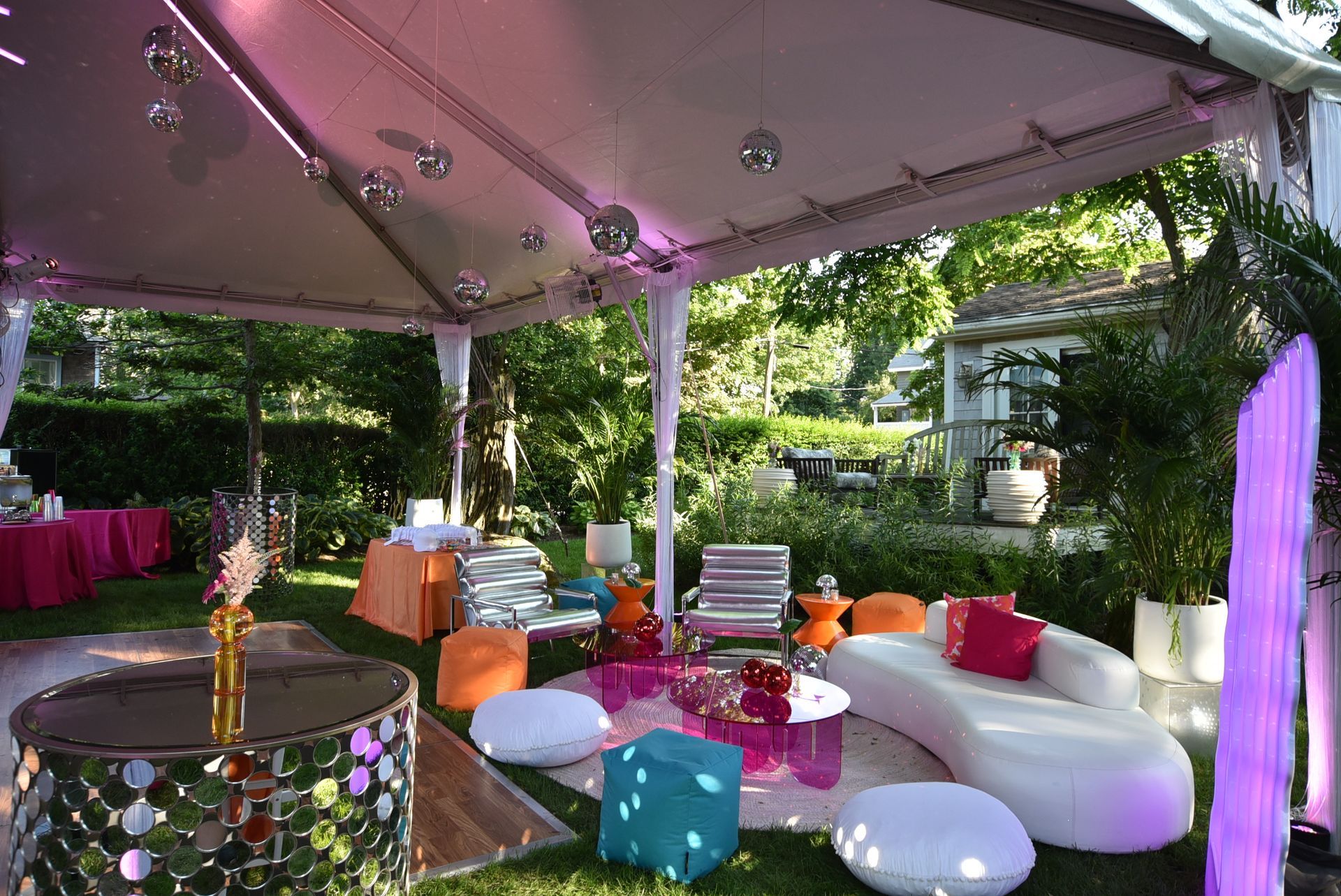 Party tent with disco balls, colorful seating, and outdoor setting.